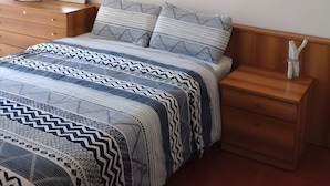 A bedroom with a bed, bedside tables, a hanging light, and two framed pictures on the wall.