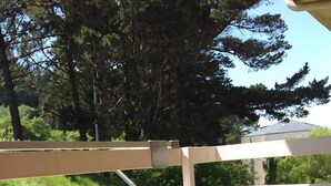 A balcony with a white railing, a brick base, and a wooden post.