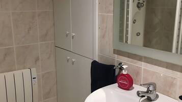 Een badkamer met een wit wastafel, een spiegel, een douche en een handdoekhouder.