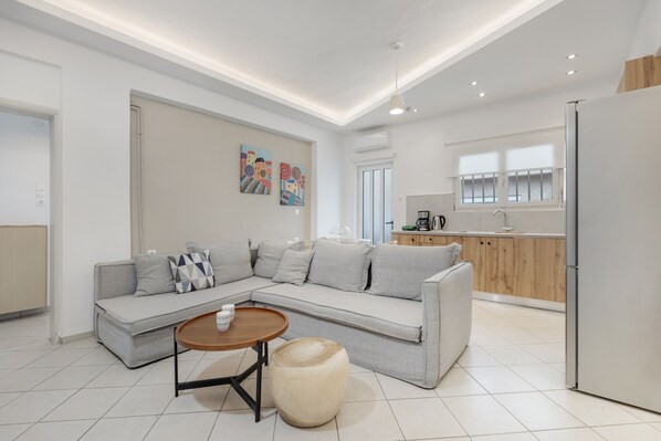 A modern living room with a sectional sofa, a round wooden coffee table, and a small round ottoman.