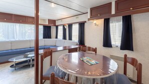 Une pièce avec une table ronde, des chaises, un canapé et une fenêtre avec des rideaux.
