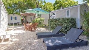 Un espace patio comprenant deux chaises longues, une table avec des chaises et un coin salon abrité.