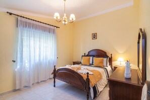 Un dormitorio con una cama de madera, una mesita de noche, una lámpara y un espejo.