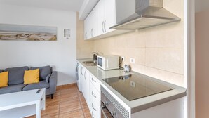 A compact kitchen with a microwave, stove, and sink.