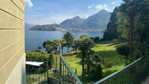 A balcony with a view of a lake, mountains, and a distant town. - Apartment 'Tarlarini' with Private Terrace, Private Garden and Wi-Fi (Laveno-Mombello)