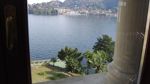 A lake with a town and mountains in the background, viewed from a balcony with a column in the foreground. - Apartment 'Tarlarini' with Private Terrace, Private Garden and Wi-Fi (Laveno-Mombello)