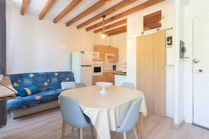 Un espace de vie compact comprenant un coin cuisine, un canapé, une table à manger et un plafond en bois.