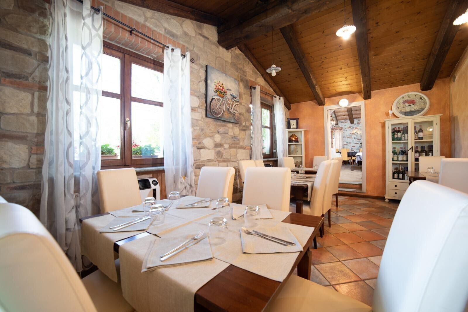 A dining area with stone walls, wooden beams, and a table set for six.