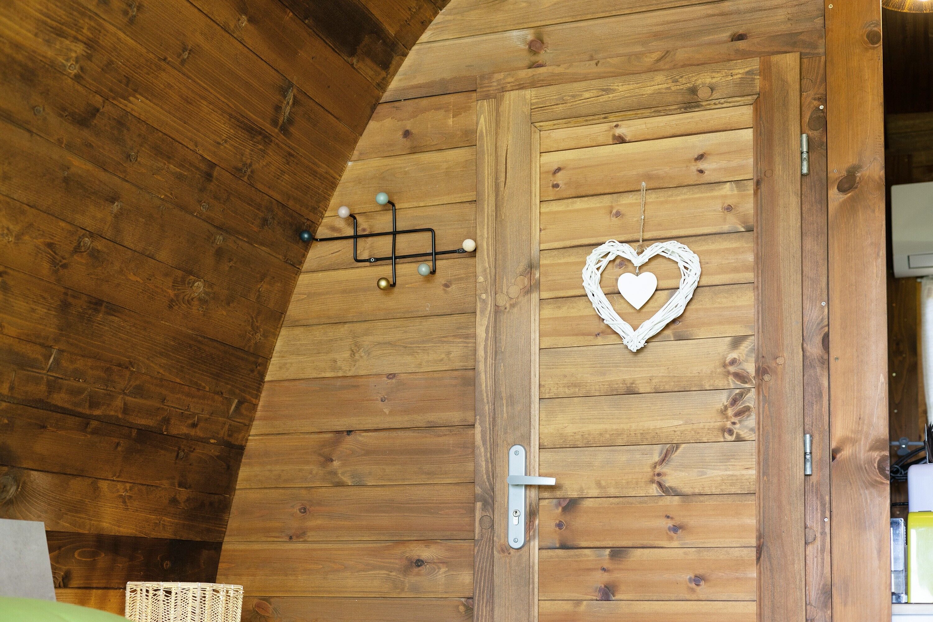 A wooden door with a heart-shaped decoration, a metal handle, and a wall-mounted light fixture.