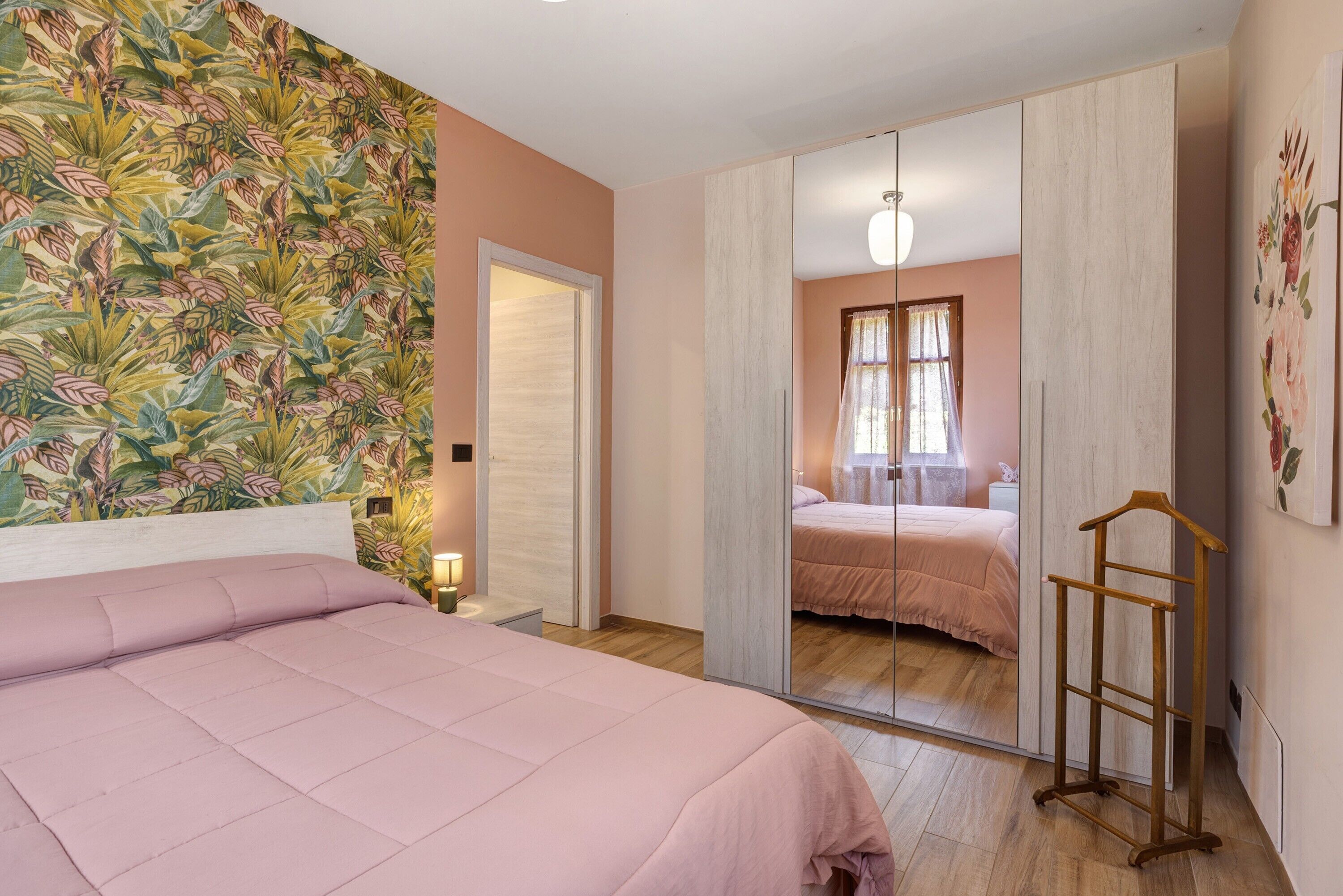 Un dormitorio con cama, armario, espejo y perchero.