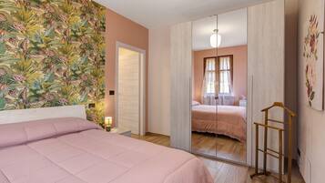 Un dormitorio con cama, armario, espejo y perchero.