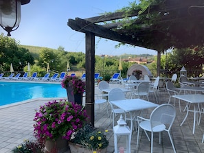 Un espace aménagé au bord de la piscine, avec des chaises longues, des tables et une pergola.