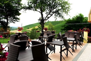 Une terrasse extérieure aménagée avec des meubles en osier, offrant une vue sur des collines ondoyantes.