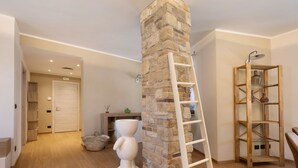 A room with a stone pillar, a white ladder, a wooden shelf, and a white sculpture. - Apartment 'Due Camere' with Mountain View, Shared Pool and Shared Garden (Dogliani)
