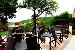 An outdoor patio with wicker furniture and a view of rolling hills.