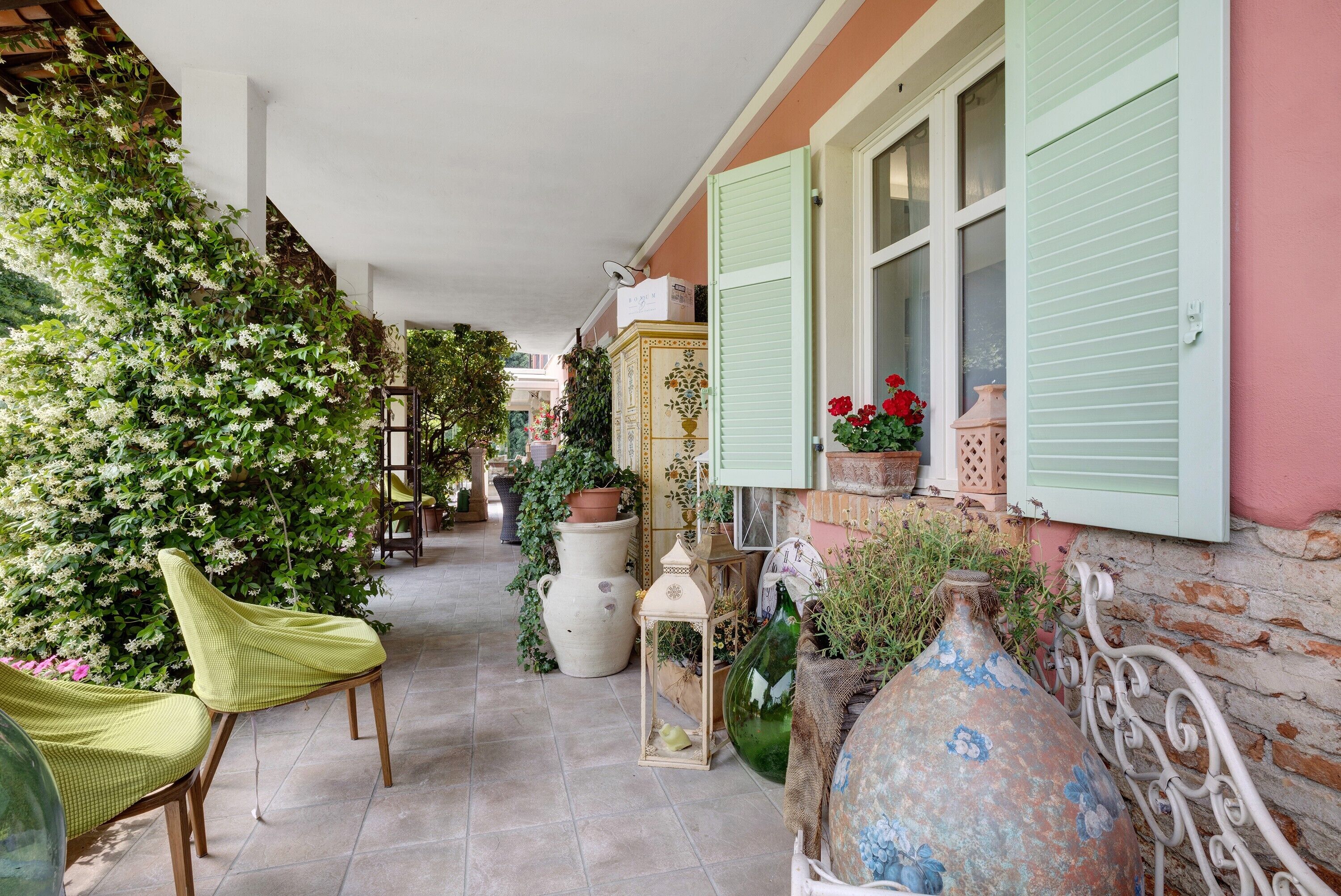 A covered outdoor area with chairs, potted plants, and decorative vases.