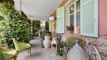 A covered outdoor area with chairs, potted plants, and decorative vases.
