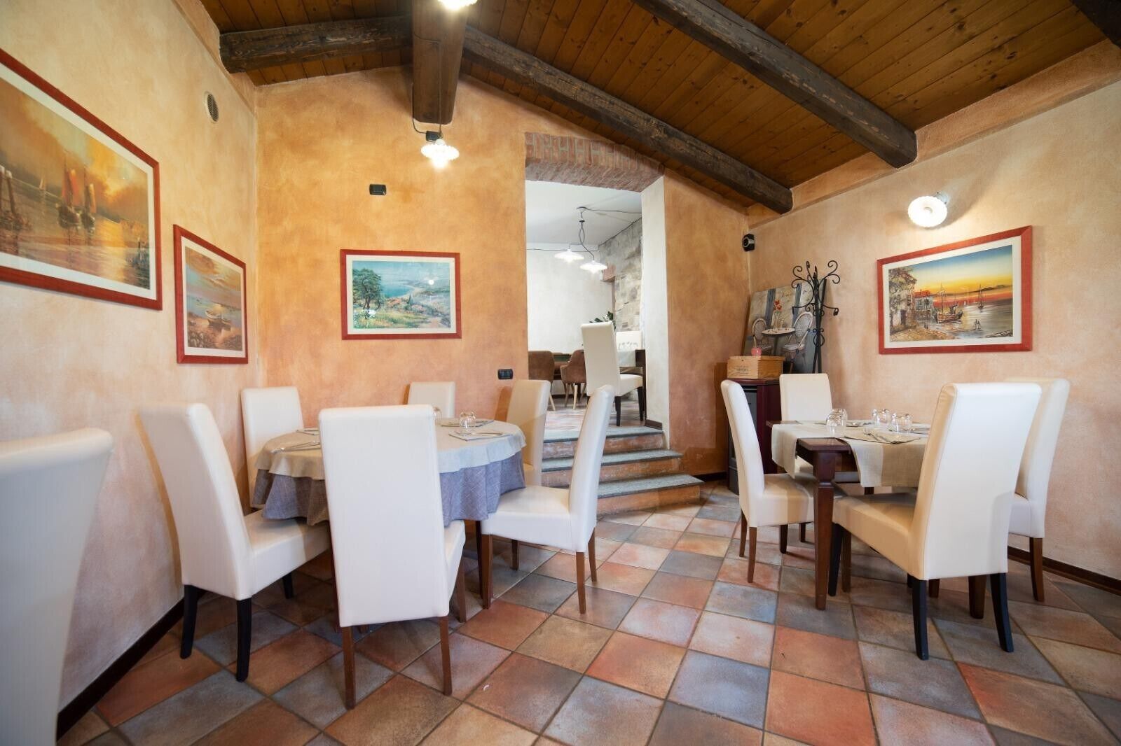 A dining area with white chairs, a round table, and a wooden ceiling.