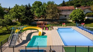 A swimming pool with a slide, a separate pool area, and a fenced deck with lounge chairs. - 3★ Campsite in Périgord Noir – Mobile Home with Pool, Fishing & Family Activities (Saint-Martial-de-Nabirat)