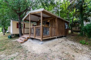 Une cabane en bois avec une véranda, un espace clôturé et un sol en terre battue.