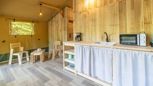Una carpa con interior de madera, un lavamanos, un microondas y sillas.