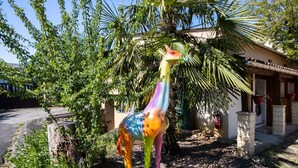 Una estatua de una colorida jirafa en un jardín con una casa al fondo.