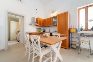 A kitchen with wooden cabinets, a dining table with chairs, and a window with plants.