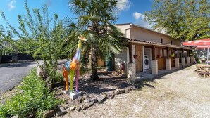 A building with a covered patio, palm trees, and a giraffe statue.