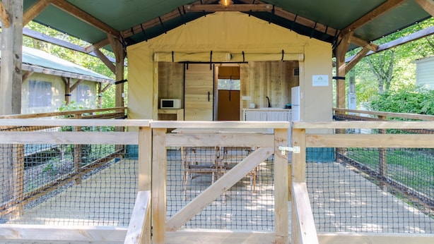 A covered outdoor area with a wooden structure, a netted enclosure, and a sign indicating a 'Sustainable' facility.