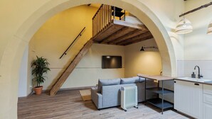Eine moderne Küche mit Holztreppe, einem grauen Sofa und einem Blumentopf.