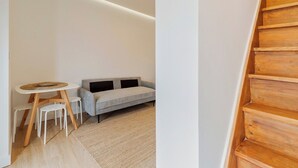 Un intérieur moderne avec un canapé, une petite table ronde et un escalier en bois.