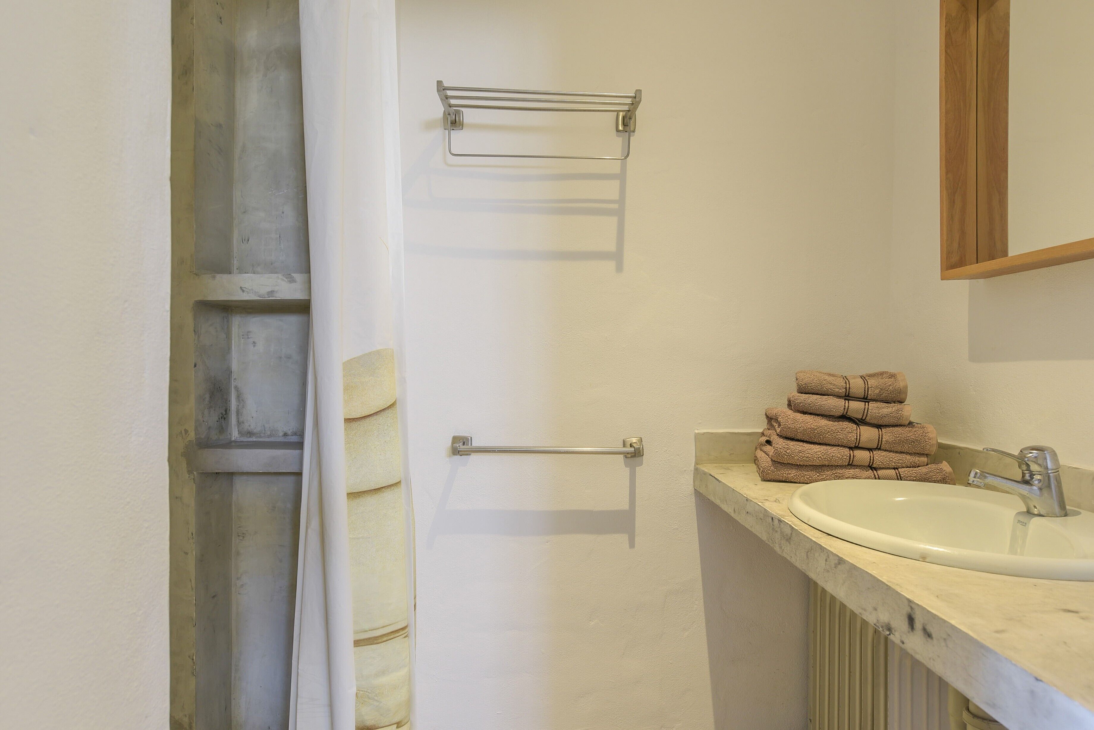 A bathroom with a white sink, a towel rack, and a stack of towels.