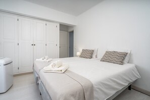 Hotellihuone, jossa on sänky, vaatekaappi, pesukone ja kylpyhuone.