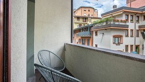 Varanda com duas cadeiras e vista para edifícios próximos, sob um céu claro.