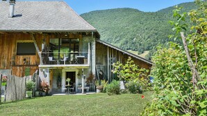 A wooden house with a balcony, a front porch, and a mountain backdrop. - Le Fayard Loft – Character Apartment in Renovated Farmhouse, Hot Tub, Mountain Views (Aillon-le-Jeune)