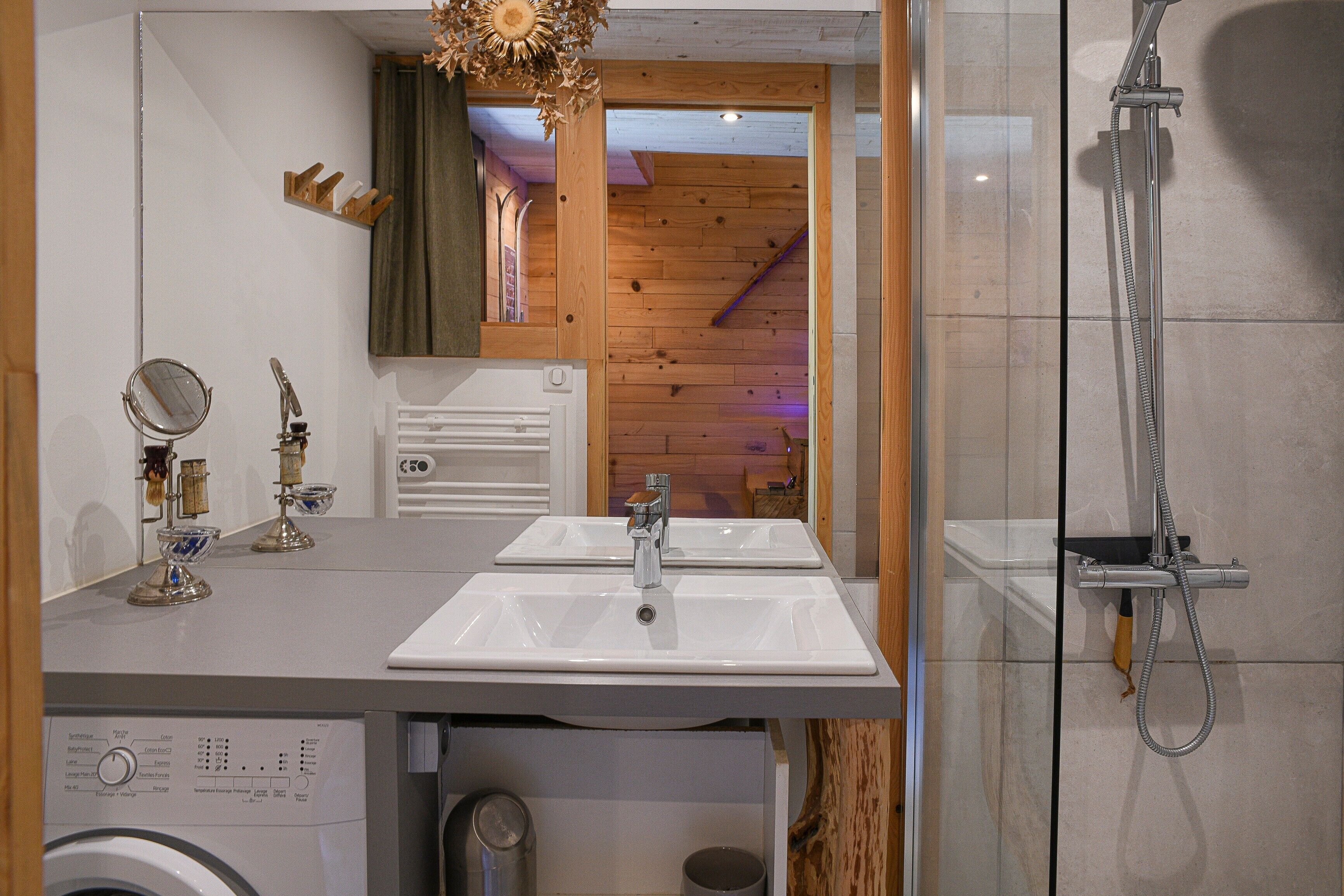Een badkamer met twee wastafels, een spiegel, een douche en een wasmachine.