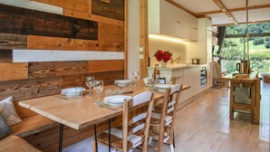 A wooden dining table set with plates, glasses, and cutlery, surrounded by chairs. - Le Fayard Loft – Character Apartment in Renovated Farmhouse, Hot Tub, Mountain Views (Aillon-le-Jeune)