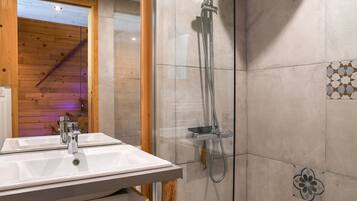 Un bagno con un lavandino bianco, una cabina doccia in vetro e finiture in legno.