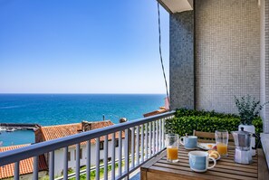 Un balcon avec vue sur la mer, une table avec des produits pour le petit-déjeuner et une machine à café.