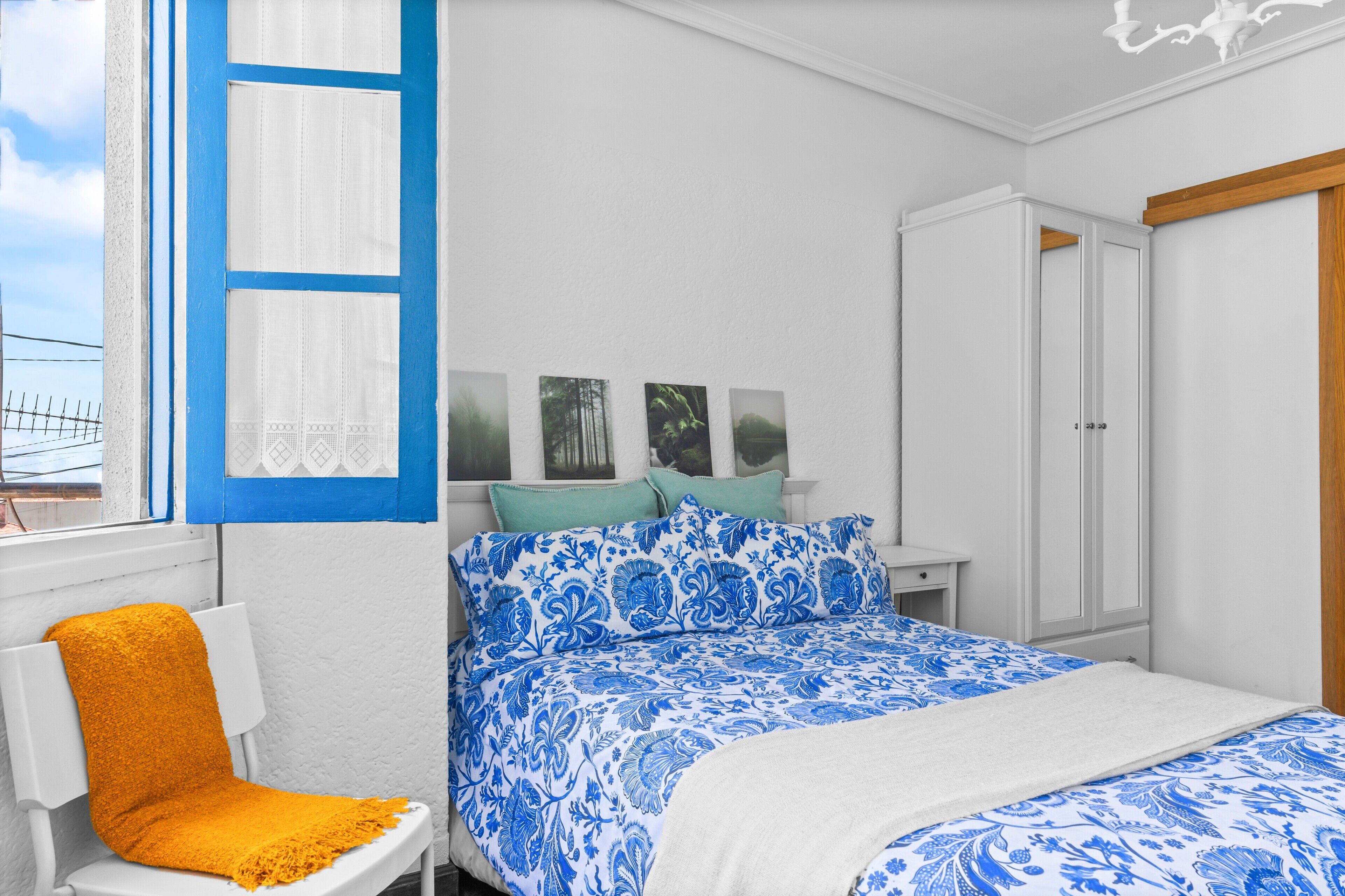 Quarto com cama, cadeira, guarda-roupa e janela com cortinas.