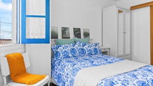 A bedroom with a bed, a chair, a wardrobe, and a window with curtains. - Holiday Home 'El Fontanin, Tu Descanso Marinero' with Private Terrace (Lastres)