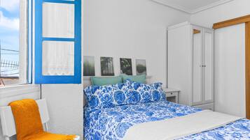 Quarto com cama, cadeira, guarda-roupa e janela com cortinas.