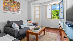 A living room with a sofa, coffee table, TV, and artwork on the wall. - Holiday Home 'El Fontanin, Tu Descanso Marinero' with Private Terrace (Lastres)