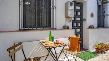 Uma pequena área externa com mesa, cadeiras e um banco.