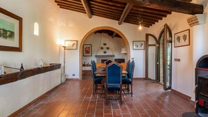 A dining area with a brick floor, wooden ceiling beams, and a table with chairs. - Villa 'Bianca Luce' with Private Pool, Private Terrace and Wi-Fi (Santa Luce)