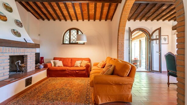 A living room with a fireplace, two sofas, a patterned rug, and exposed wooden beams. - Villa 'Bianca Luce' with Private Pool, Private Terrace and Wi-Fi (Santa Luce)