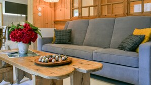 En stue med en grå sofa, et træbord og en vase med røde blomster.
