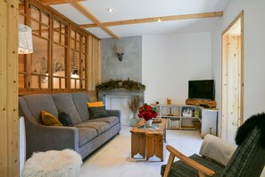 A living room with a sofa, a coffee table, a television, and a fireplace. - Ciméléon Haut Cottage – Authentic Mountain Charm, Mountain View, Terrace, Sleeps 6 (Aillon-le-Jeune)