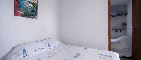 A bedroom with a bed, a painting, and a door leading to a bathroom.