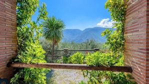 A view through a brick archway with a wooden railing, leading to a mountainous landscape.